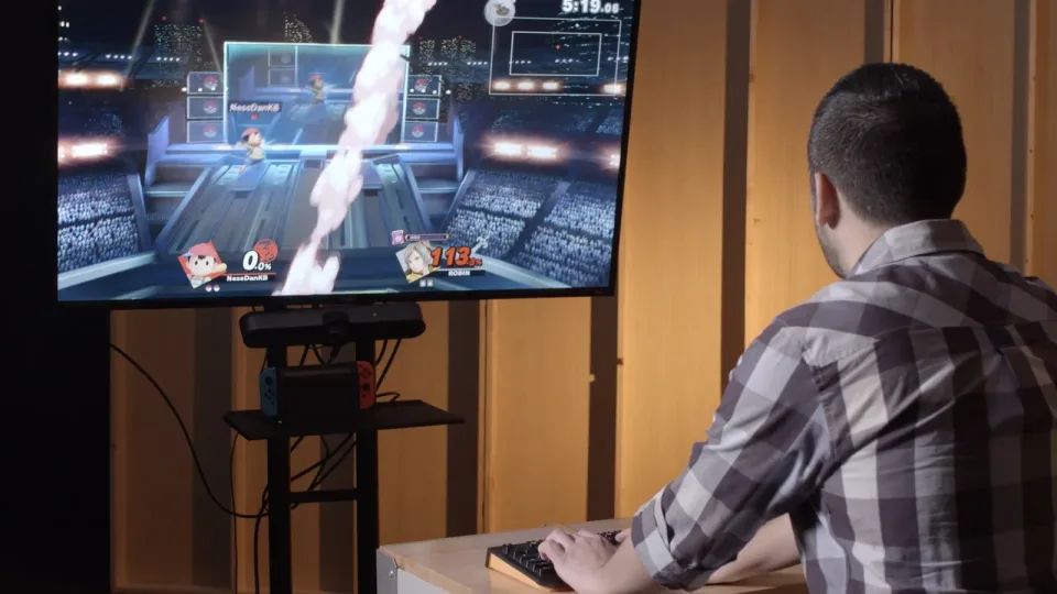 Daniel playing Super Smash Bros. Ultimate with a keyboard and a docked Nintendo Switch, from the original campaign video.