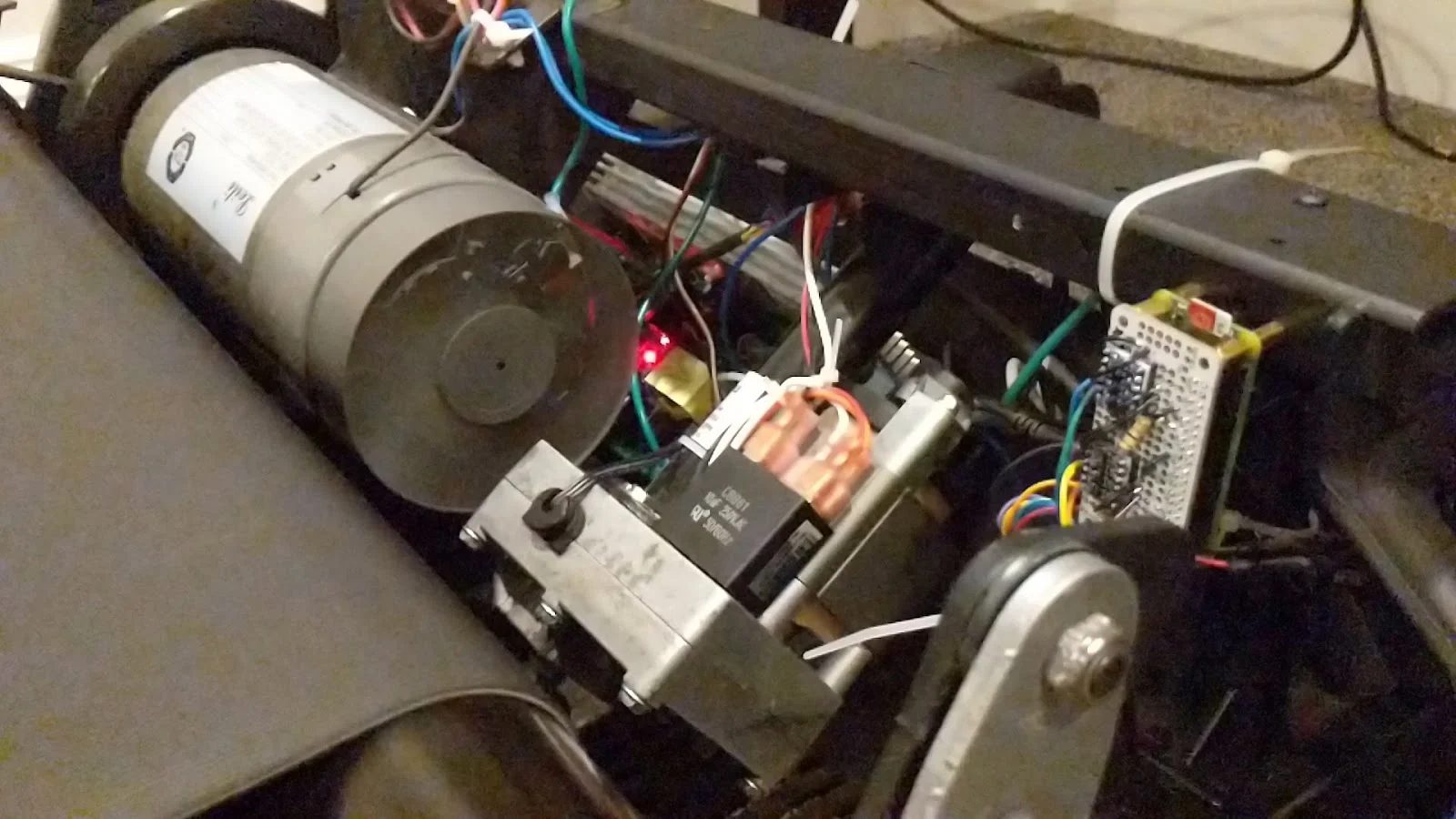 The treadmill's exposed motor, control wiring, and Raspberry Pi prototype board.